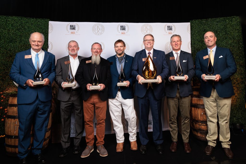 The 2026 Kentucky Bourbon Hall of Fame honorees and family representatives holding their awards on stage at the Marriott Louisville East